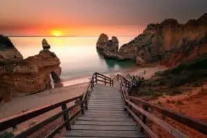Wooden staircase leading down to the golden coves and cliffs at Ponta da Piedade in the Algarve region of Portugal during a beautiful sunset, popular spot for private Portugal tours