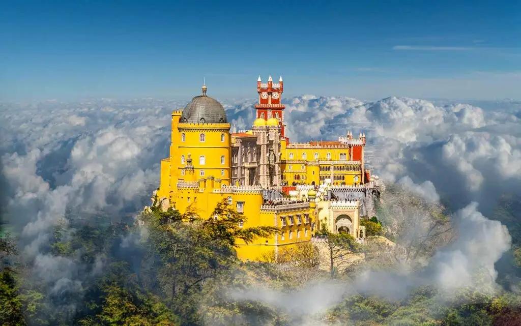 Colorful Pena Palace above the clouds in Sintra, Portugal, a famous tourist attraction and UNESCO World Heritage site.