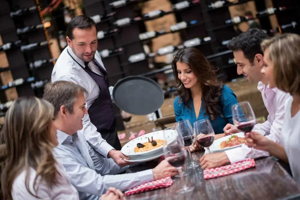 Group enjoying paella and red wine at a restaurant during a food and wine tour in Portugal
