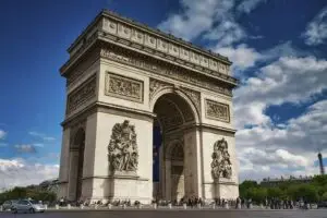 Arc de Triomphe in Paris France with tourists and city landmarks under a blue sky
