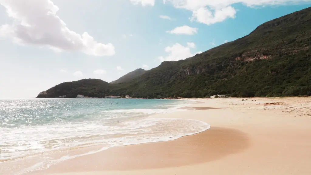 Praia da Figueirinha sandy beach with turquoise sea and lush green hills in Setúbal Portugal on a sunny day, popular coastal destination for nature and beach tours