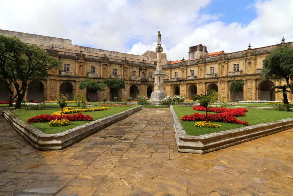 Cloister garden of the Monastery of Santa Clara-a-Velha in Coimbra Portugal with ornate stone architecture and colorful flower beds