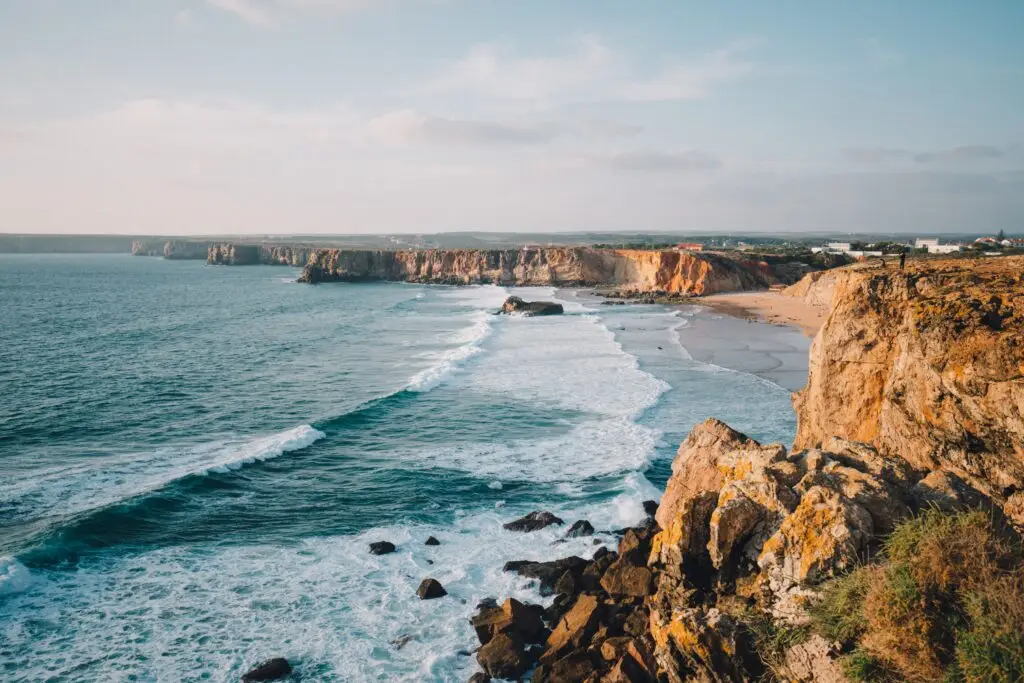 Scenic view of Tonel Beach with rocky cliffs, ocean waves, and golden coastline in Sagres, Algarve, Portugal
