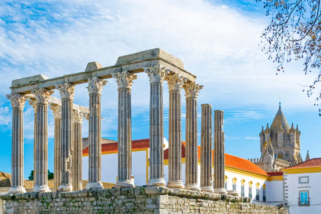 Roman Temple of Évora with the Évora Cathedral in the background on a sunny day, historic landmark and popular tourist attraction in Portugal