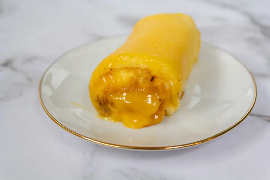 Close-up of traditional Portuguese dessert Torta de Azeitão, a yellow sponge cake roll filled with egg custard, served on a white plate, typical pastry from Portugal
