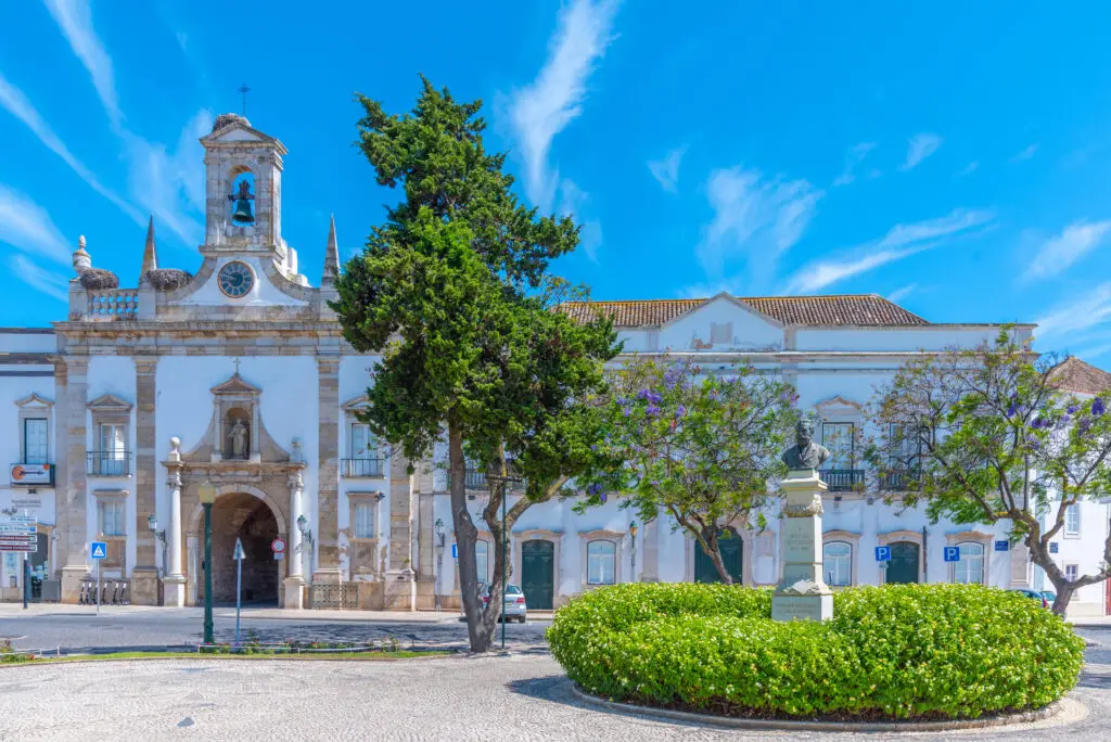 Arco da Vila in Faro Portugal with historic architecture, bell tower and statue in a sunny town square