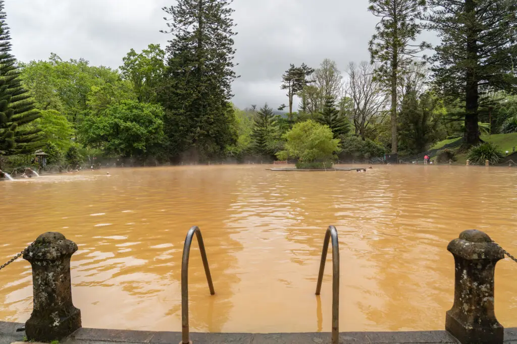 Thermal mineral pool surrounded by lush greenery at Parque Terra Nostra in Furnas, Sao Miguel Island, Azores, Portugal