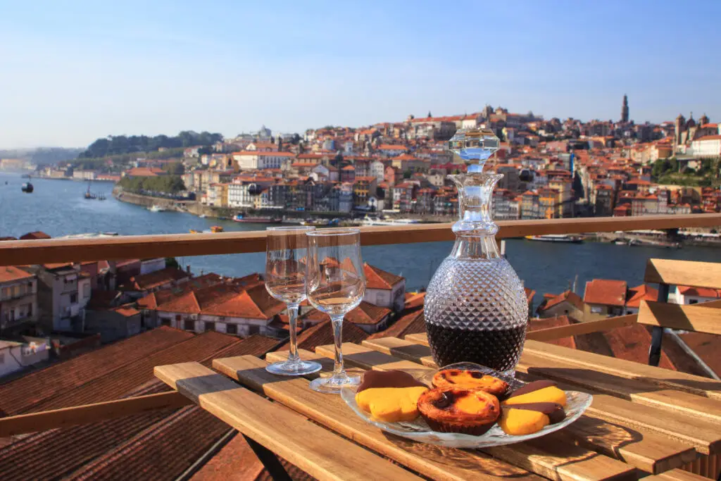 Glass decanter of Port wine with pastries on a terrace overlooking the Douro River and city of Porto, Portugal