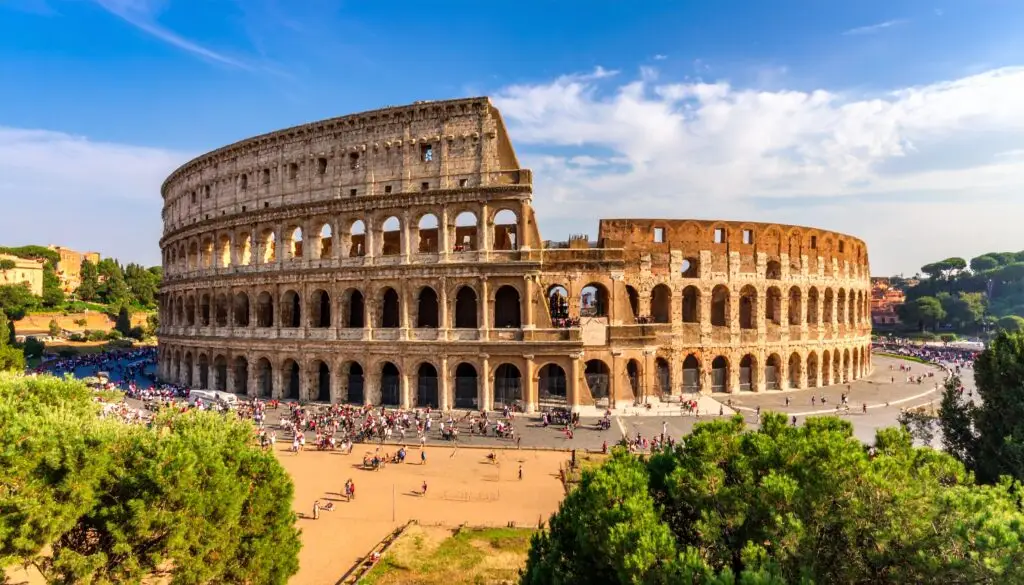 Ancient Roman Colosseum in Rome Italy with tourists exploring the historic amphitheater and sunny blue sky background