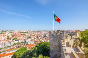 Portuguese flag flying above São Jorge Castle with panoramic view of Lisbon city, Portugal