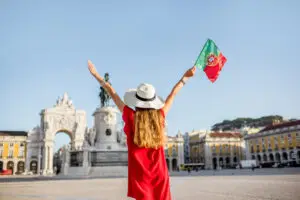 Woman celebrating at Praça do Comércio in Lisbon Portugal holding Portuguese flag during a city tour