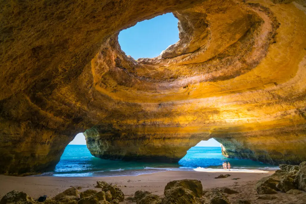 Tourists exploring Benagil Cave with golden cliffs and turquoise sea in Carvoeiro, Algarve, Portugal