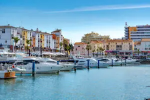 Luxury yachts docked at Vilamoura Marina in Algarve Portugal with waterfront buildings and clear blue sky