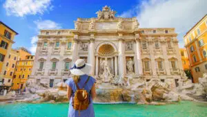 Tourist admiring the famous Trevi Fountain in Rome Italy on a sunny summer day surrounded by historic architecture