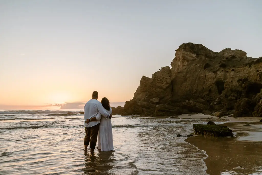 Couple in love embracing at sunset on Praia de Paredes da Vitória beach in Portugal, enjoying a romantic moment by the ocean during a private Portugal tour