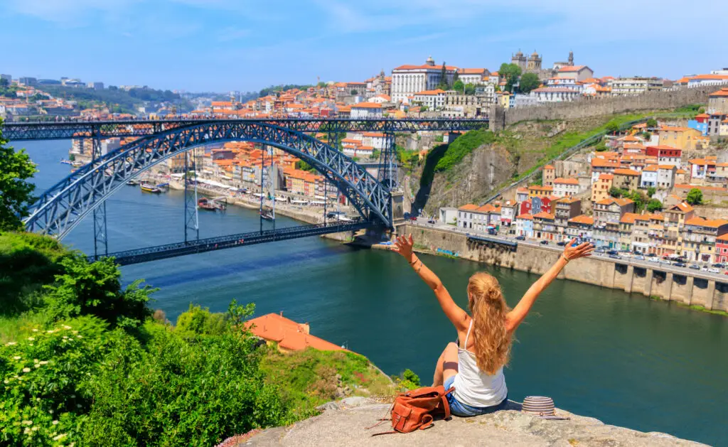 Woman tourist enjoying panoramic view of Dom Luís I Bridge and colorful old town of Porto, Portugal, during a scenic city tour with Private Portugal Tours