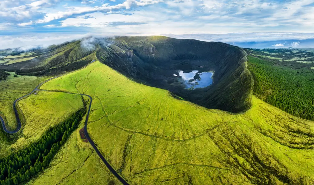 Aerial view of the green volcanic crater Caldeira on Faial Island in the Azores, Portugal, at sunrise showcasing lush landscapes and scenic natural beauty