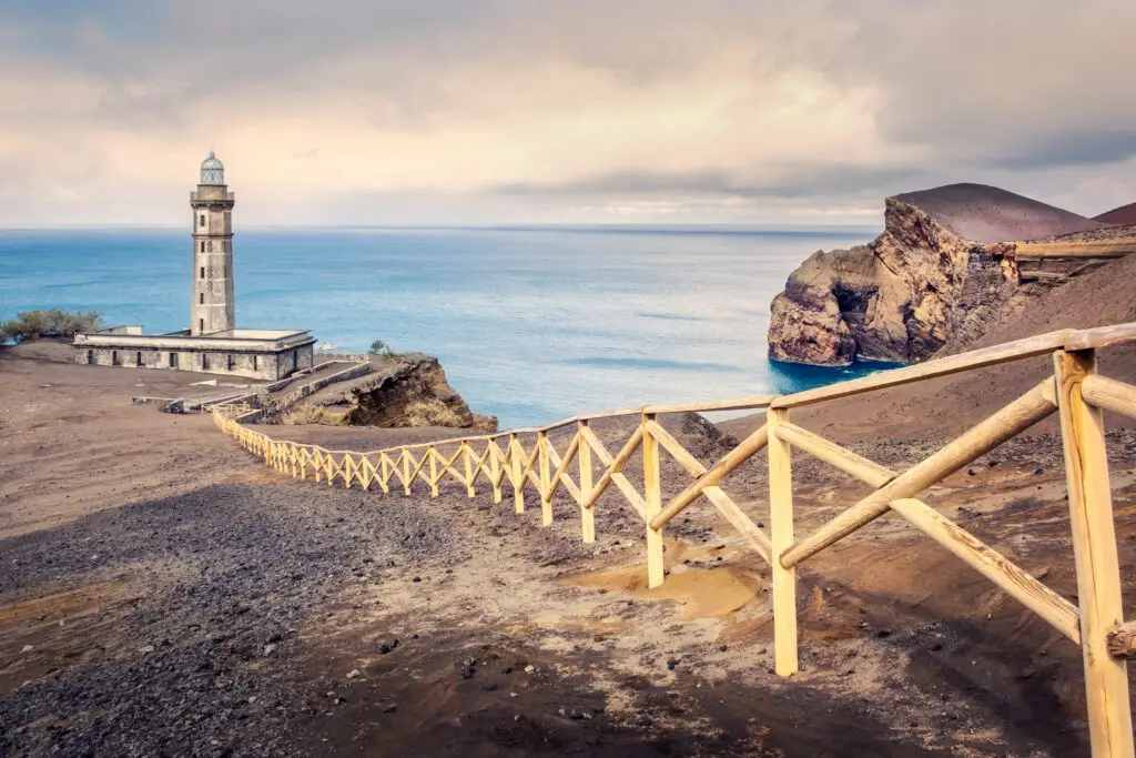 Scenic view of the Lighthouse of Ponta dos Capelinhos on Faial Island, Azores, Portugal with dramatic sky, volcanic landscape, and ocean backdrop