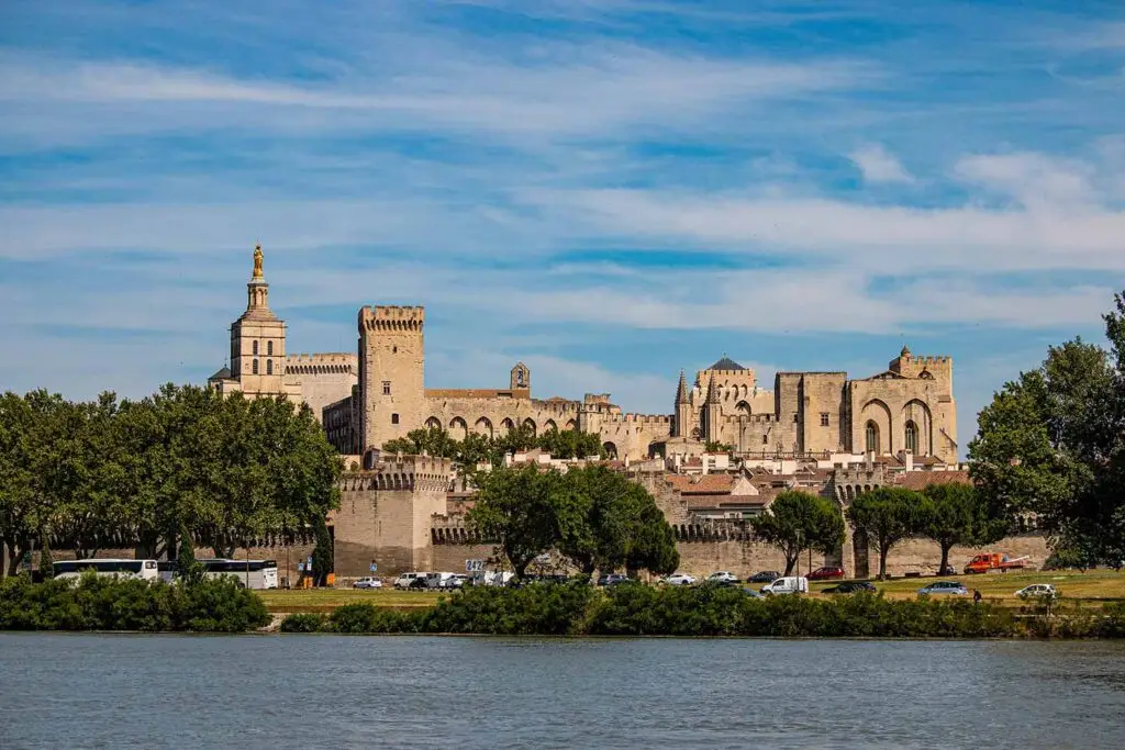 View of the historic Papal Palace and medieval city walls of Avignon, France, seen from across the Rhône River on a sunny day