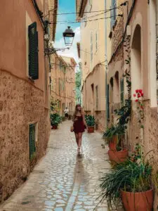 Tourist walking through a charming narrow cobblestone street with traditional Portuguese architecture and flower pots in Portugal
